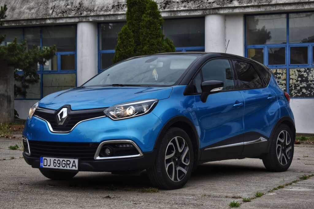 A blue Renault car parked outside a building with a Romanian license plate.