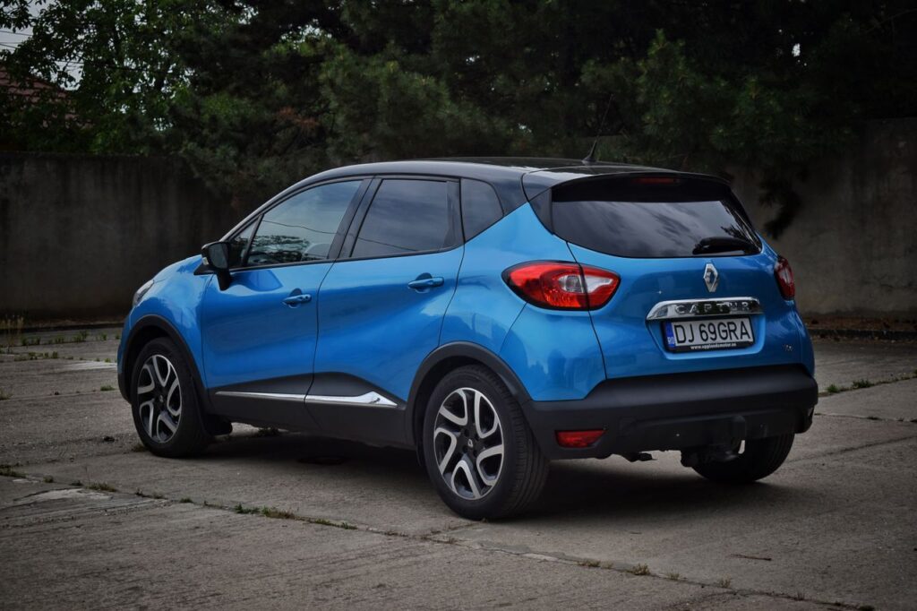 A sleek blue Renault Captur car parked on a concrete surface, outdoors.