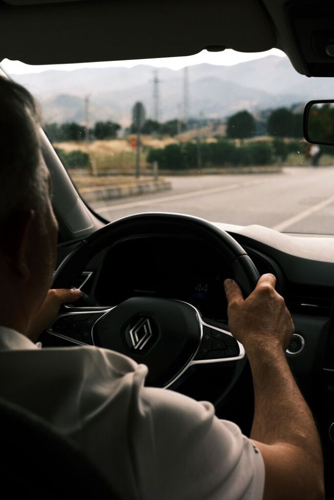 Driver on a scenic road with mountains visible in the distance.